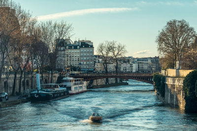 Bridge over river by buildings in city against sky