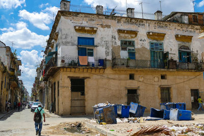 People on street amidst buildings in city against sky