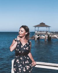 Young woman standing by sea against sky