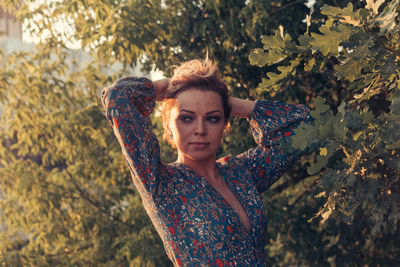 Portrait of young woman standing against plants