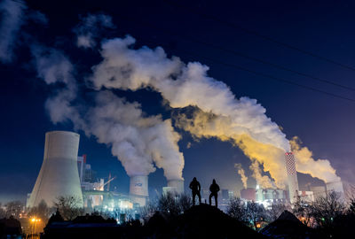 Smoke emitting from factory against sky