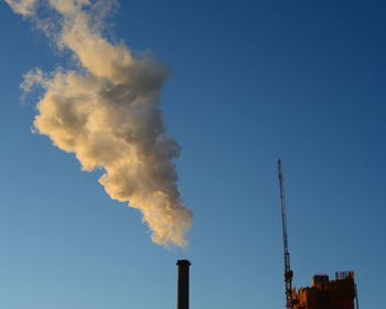 Low angle view of smoke emitting from factory against sky