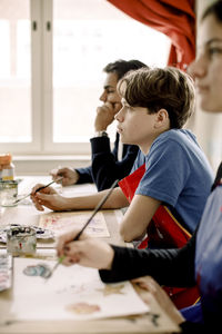 Side view of male teenage student attending art class at high school