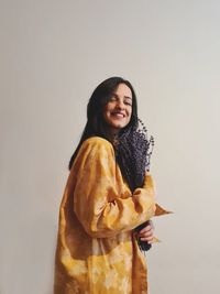 Smiling young woman standing against white background