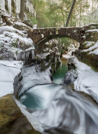 Arch bridge over river stream during winter