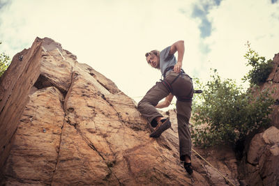 Full length of young man on rock against sky