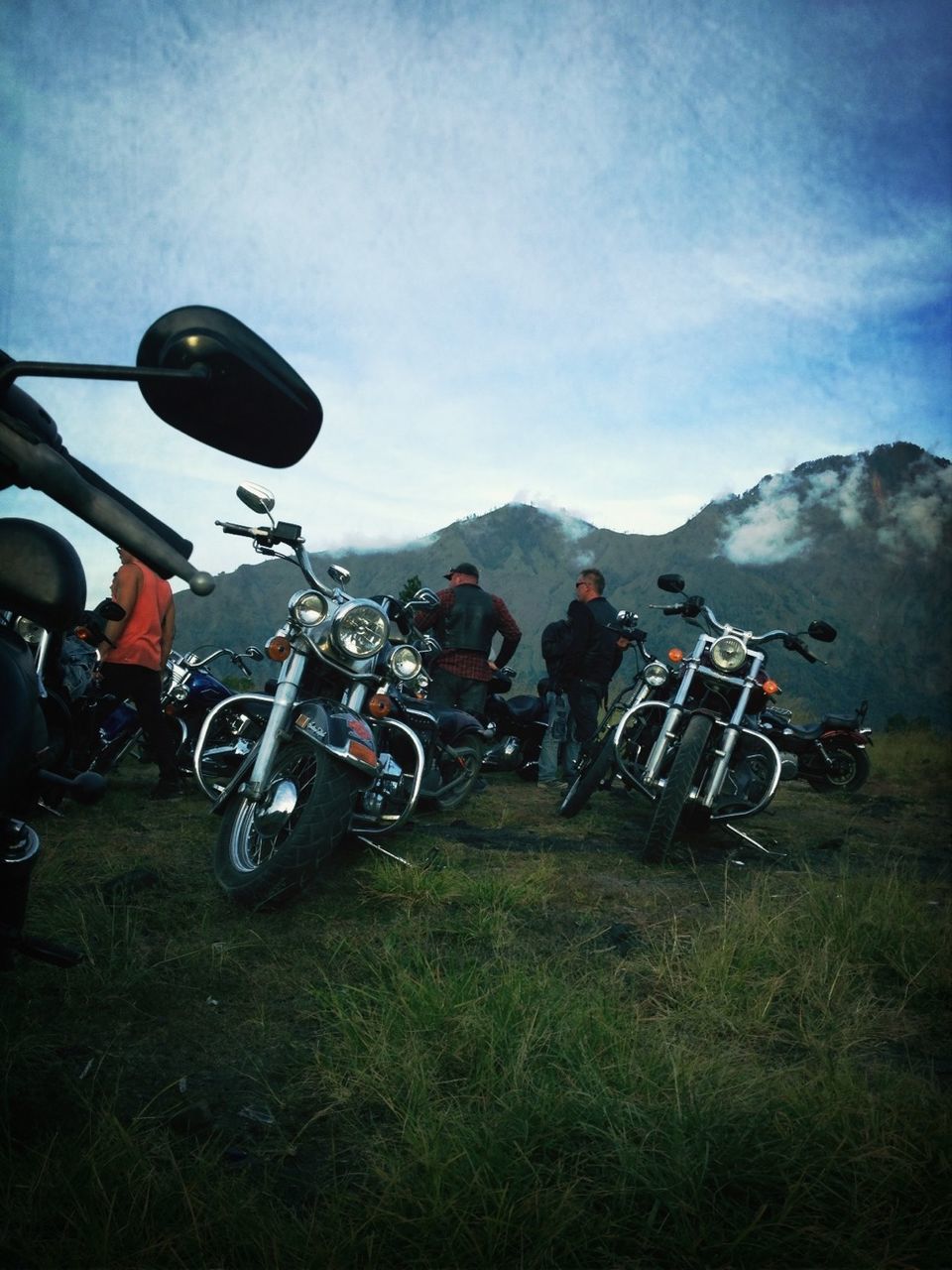 transportation, land vehicle, mode of transport, sky, grass, bicycle, men, mountain, landscape, leisure activity, field, lifestyles, stationary, travel, cloud - sky, motorcycle, parked, day, mountain range