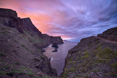 Rock formations by sea against sky during sunset