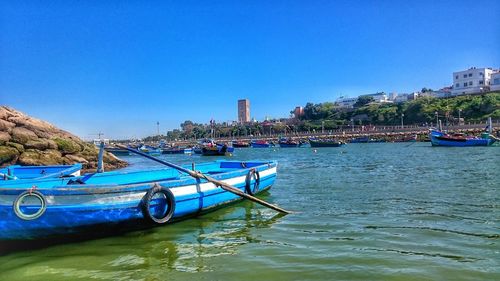 Boats moored in sea against clear blue sky