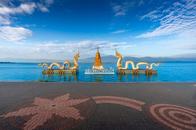 Naga statue with bright sky, clouds, mountains background and fresh water lake 