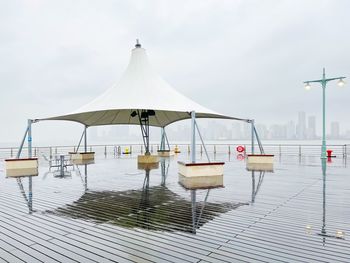 Deck chairs by sea against sky during rainy season