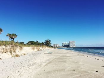 Surface level of calm beach against clear blue sky