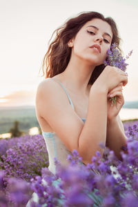 A beautiful young girl against the sunset and a beautiful sky in a lavender field. 