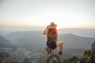 Switzerland, grosser mythen, young woman on a hiking trip sitting on a rock at sunrise