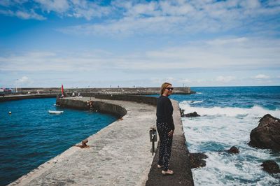 Full length of woman walking on retaining wall at pier