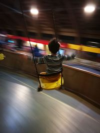 Rear view of man on illuminated bus at night