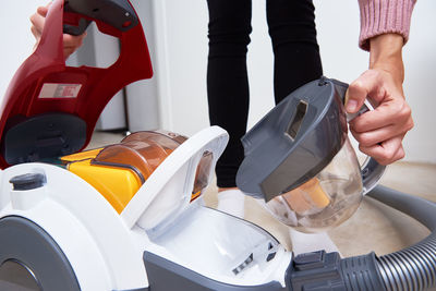 Woman takes out container of dust from vacuum cleaner