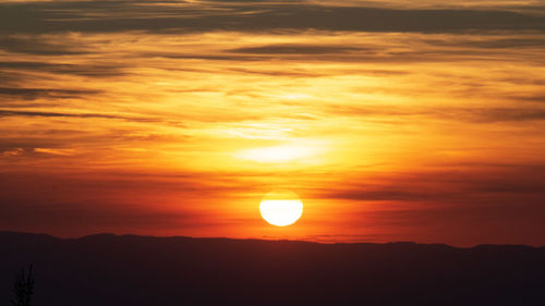 Scenic view of silhouette mountains against orange sky