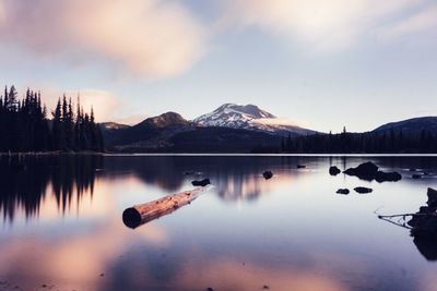 Scenic view of lake by snowcapped mountains against sky