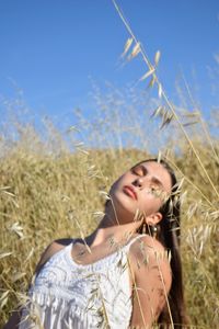 Young woman with eyes closed by plants on field