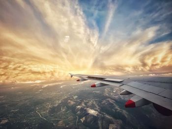 Airplane flying over clouds during sunset