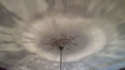 Low angle view of trees against cloudy sky