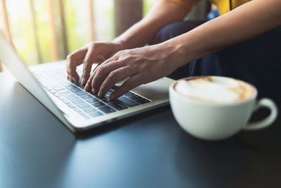 Midsection of person holding coffee cup on table