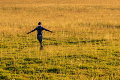 Rear view of man jumping on field