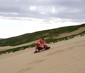 Young woman sitting on sand against sky