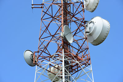 Low angle view of communications tower against clear blue sky