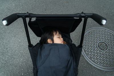 High angle view of girl sleeping in stroller on road