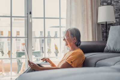 Side view of young woman looking through window