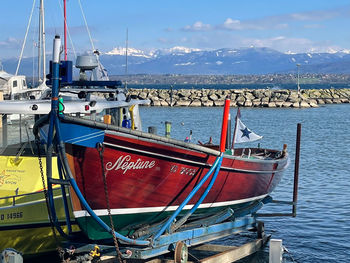 Sailboats moored at harbor against sky