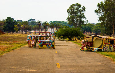 People on road by trees against sky