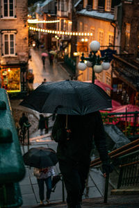 Man with umbrella walking in city during rainy season