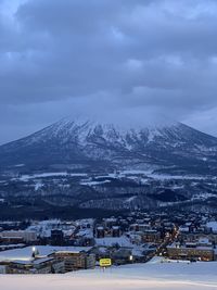 Aerial view of townscape by snowcapped mountain against sky