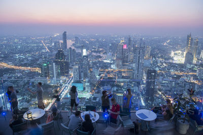 Aerial view of illuminated buildings in city at dusk