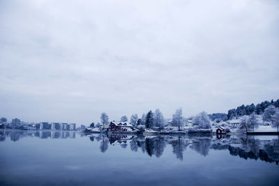 Reflection of trees in lake against sky in city