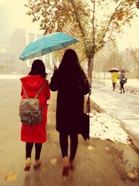 Rear view of people walking on road in city