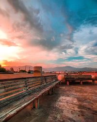 Empty benches at san gabriel valley airport against cloudy sky during sunset