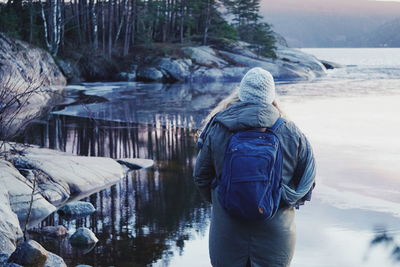 Rear view of woman standing by lake during winter