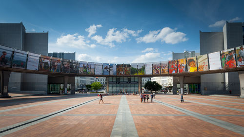 People on modern buildings in city against sky