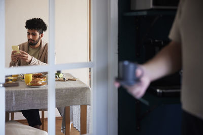 Man using phone while having breakfast at home