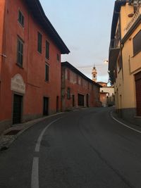 Empty road amidst buildings against sky in city