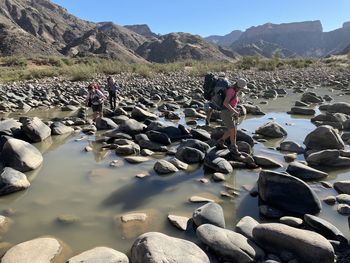 Hikers on rocks crossing river