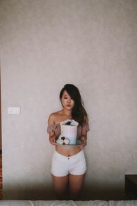 Young woman standing against wall at home