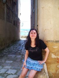 Portrait of young woman standing against wall