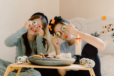 Funny sisters fooling around playing with halloween sweets.