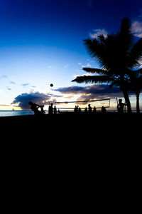 Silhouette people on beach against sky during sunset