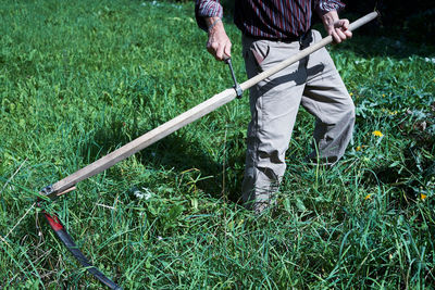 The man cutting grass with a scythe. background, close up.